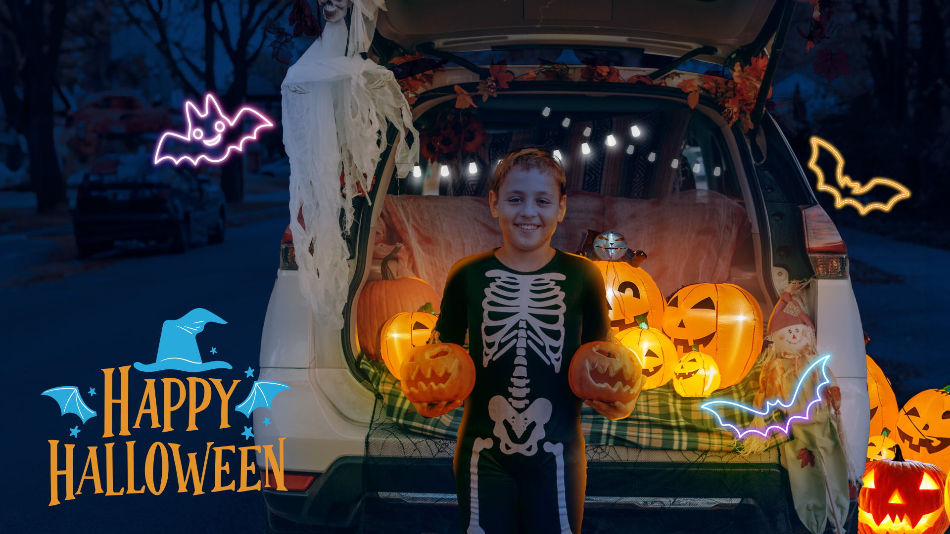 A child in a skeleton costume stands in front of a decorated car trunk filled with jack-o'-lanterns and Halloween lights during a trunk-or-treat event.

