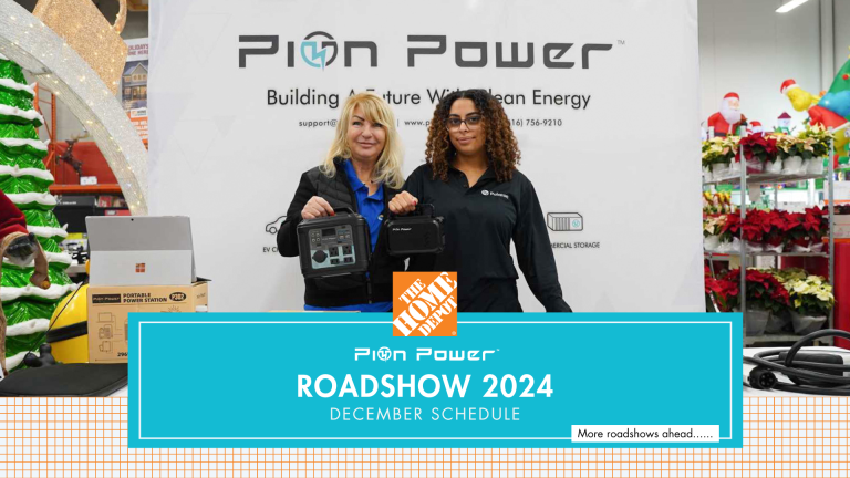 Two representatives at the Pion Power booth during a Home Depot roadshow. They are holding portable power stations and showcasing clean energy products, including EV chargers and accessories, against a branded backdrop. Holiday decorations and displays are visible in the background